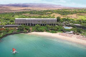 a hotel on a beach with a boat in the water at Mauna Kea Beach Hotel, Autograph Collection in Hapuna Beach
