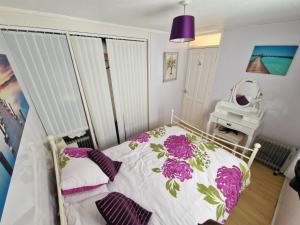a small bedroom with a bed with purple flowers at 60 upperlakeside glan gwna in Caernarfon