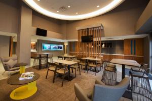 SpringHill Suites by Marriott Seattle Issaquah في إساكوا: مطعم بطاولات وكراسي وتلفزيون بشاشة مسطحة