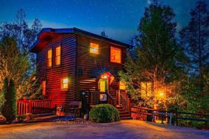 una casa di tronchi di notte con le luci accese di Stunning Mountain Cabin w/ Views a Gatlinburg