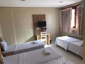 a hotel room with two beds and a television at Rede Andrade Goiania Centro in Goiânia