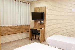 a room with a desk with a television and a bed at Rede Andrade Goiania Centro in Goiânia