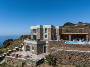 a stone house on a hill with a swimming pool at Acron Andros - Luxury Villa with Private Pool in Andros