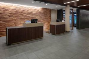 a lobby with two reception desks and a brick wall at Courtyard Cincinnati Mason in Mason