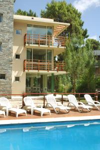 a resort with a swimming pool and chairs and a building at Complejo Aroma's in Mar de las Pampas