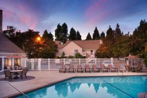 uma piscina com cadeiras, uma mesa e uma cerca em Residence Inn Sunnyvale Silicon Valley II em Sunnyvale