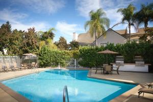 una piscina en un patio con sillas y sombrillas en Residence Inn Sunnyvale Silicon Valley II, en Sunnyvale