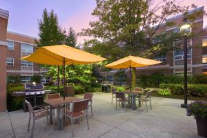 un patio avec des tables et des chaises et des parasols jaunes dans l'établissement TownePlace Suites by Marriott Mississauga-Airport Corporate Centre, à Mississauga