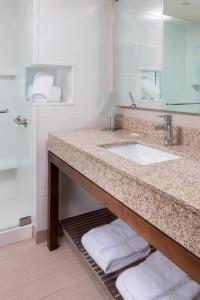 a bathroom with a sink and a mirror and towels at Courtyard by Marriott Bismarck North in Bismarck