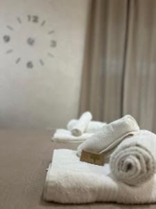 einen Haufen Handtücher auf einem Bett mit einer Uhr in der Unterkunft Scicocco Sweet Home in Bagnoli del Trigno