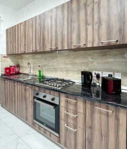 uma cozinha com armários de madeira e um forno com placa de fogão em The Hazel penthouse with private jacuzzi em Birkirkara