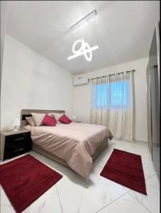 um quarto branco com uma cama e tapetes vermelhos em The Hazel penthouse with private jacuzzi em Birkirkara