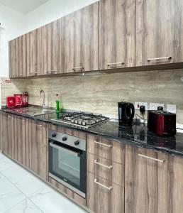 uma cozinha com armários de madeira e um forno com placa de fogão em The Hazel penthouse with private jacuzzi em Birkirkara