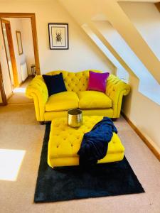sala de estar con sofá amarillo y mesa en 1 Loch Ness Heights, en Inverness