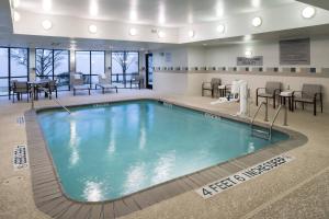 - une piscine dans une chambre d'hôtel dotée de tables et de chaises dans l'établissement Courtyard by Marriott West Orange, à West Orange
