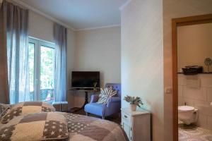 Schlafzimmer mit einem Bett, einem TV und einem Stuhl in der Unterkunft Landhotel Eifellust in Schalkenmehren