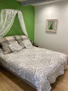 1 dormitorio con 1 cama con edredón blanco y pared verde en Le Mas aux Arômes, en Puget