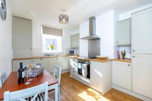 a kitchen with white cabinets and a wooden table and a dining room at The Ilkley Retreat in Ilkley