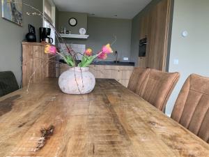 een vaas met bloemen op een houten tafel bij Gastenverblijf lânlibben in Lioessens