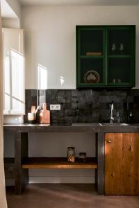 una cocina con armarios verdes y un banco de madera en Casa Uva - Boutique Guest House, en Vejer de la Frontera