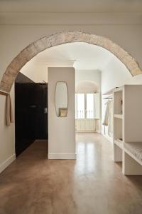 Un arco en una habitación con cama y espejo en Casa Uva - Boutique Guest House, en Vejer de la Frontera