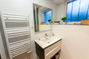 Baño blanco con lavabo y espejo en Gîte l'Améthyste 3 appartements, en Gérardmer