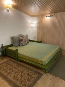 a bedroom with a green bed in a room at Rustic Retreat by Roamhome - Modern 2BHK Apartment near Naini Lake in Nainital