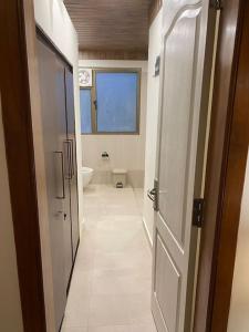 a hallway of a bathroom with a toilet and a door at Rustic Retreat by Roamhome - Modern 2BHK Apartment near Naini Lake in Nainital
