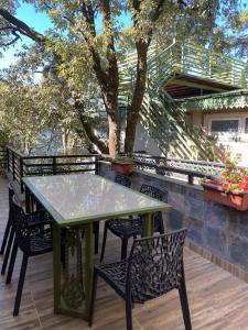 a green table and chairs on a deck with trees at Rustic Retreat by Roamhome - Modern 2BHK Apartment near Naini Lake in Nainital