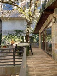 a wooden porch with a table and a tree at Rustic Retreat by Roamhome - Modern 2BHK Apartment near Naini Lake in Nainital