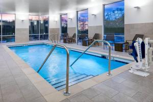 einen Pool in einem Hotel mit Tischen und Stühlen in der Unterkunft SpringHill Suites by Marriott Indianapolis Westfield in Westfield