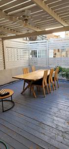 Une table et des chaises en bois sont disponibles sur la terrasse. dans l'établissement דירת סטודיו יפיפיה על גג ומרפסת שמש ברחוב הירקון, à Tel Aviv