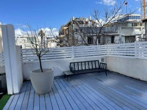 un banc sur un balcon avec un arbre dans un pot dans l'établissement דירת סטודיו יפיפיה על גג ומרפסת שמש ברחוב הירקון, à Tel Aviv