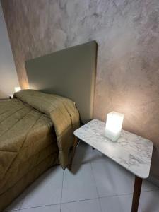 ein Schlafzimmer mit einem Bett und einem Tisch mit einer Lampe in der Unterkunft Sant'Alfonso Home in Portici