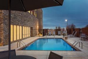 a swimming pool with an umbrella next to a building at TownePlace Suites by Marriott Memphis Southaven in Southaven
