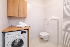 ein Badezimmer mit einer Waschmaschine und einem WC in der Unterkunft Deluxe Apartment Lipno - Lake Side Village, Frymburk nad Vltavou in Frymburk