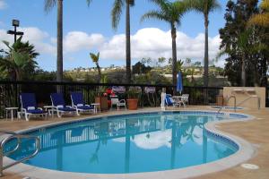 a swimming pool with blue chairs and palm trees at Fairfield Mission Viejo Orange County in Mission Viejo