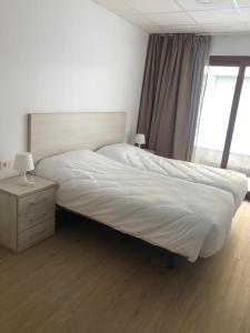 Un dormitorio con una gran cama blanca y una ventana en SOPHIE APARTAMENTOS en Burela de Cabo