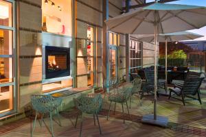 塔拉哈西的住宿－塔拉哈西市中心雅樂軒酒店，一个带椅子和遮阳伞的庭院和一个壁炉