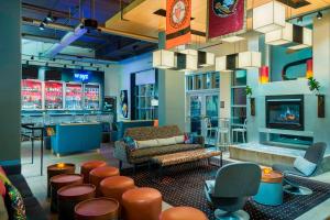 a lobby with a bar with a couch and stools at Aloft Tallahassee Downtown in Tallahassee