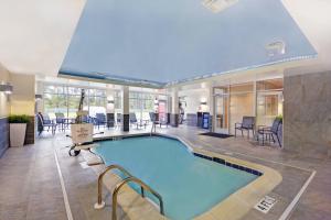 a large swimming pool in a hotel lobby with chairs and a table at Fairfield Inn & Suites by Marriott Savannah SW/Richmond Hill in Richmond Hill