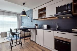 ストラスブールにあるResidence Inn by Marriott Strasbourgの白いキャビネット、テーブルと椅子付きのキッチンが備わります。