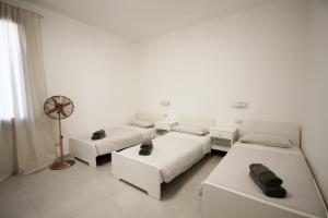 a white room with two beds and a fan at Casa Kika - Tremezzina Lenno in Lenno