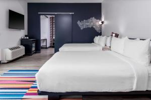 a bedroom with two white beds and a blue wall at Aloft Savannah Airport in Savannah +18 photos