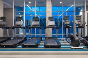 un gimnasio con varias cintas de correr y una gran ventana en Aloft Savannah Airport en Savannah