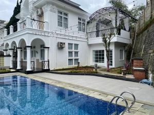 a white house with a swimming pool in front of it at Eton Asia Villas-Kota Bunga in Puncak