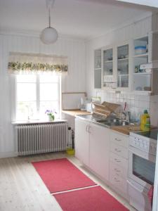 a kitchen with white cabinets and a red rug at Lillåns B&B in Örebro