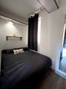1 dormitorio con cama negra y ventana en CAP ESTEREL Appartement, en Agay - Saint Raphael