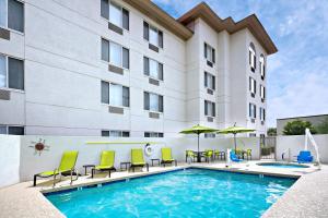a pool in front of a hotel with chairs and umbrellas at SpringHill Suites Phoenix Glendale/Peoria in Peoria