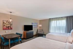 a hotel room with two beds and a desk and a television at TownePlace Suites by Marriott Panama City Beach Pier Park in Panama City Beach
